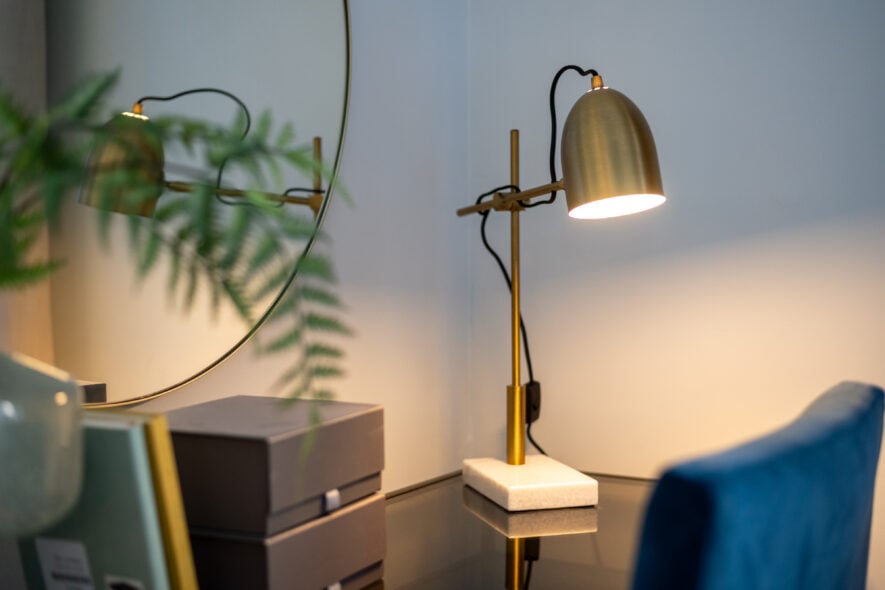 The desk of a student with a lamp on top and a blue chair beside it